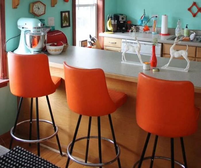 Оранжевые стулья вдоль барной стойки на кухне