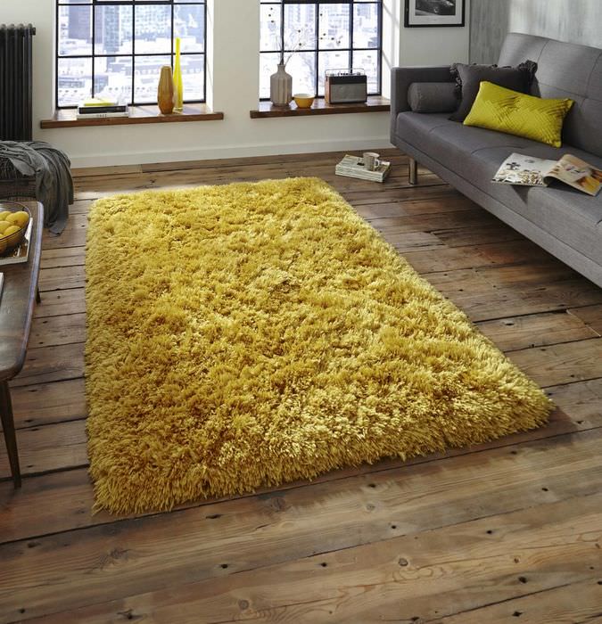 Желтый коврик на деревянном полу в темной спальне