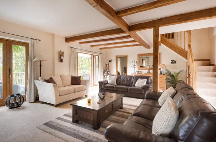 Деревянные балки на потолке гостиной с коричневым диваном