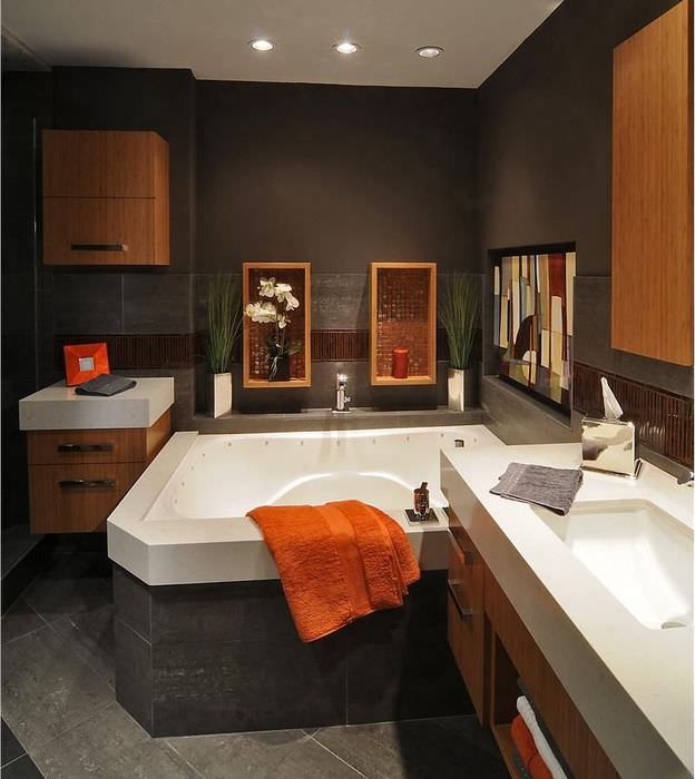 Оранжевое полотенце на краю ванны в темно-коричневой комнате