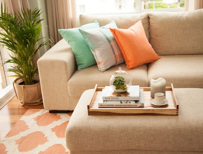Оранжевая подушка на диване с обивкой из мешковины