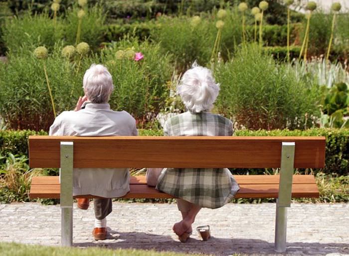 Пожилые люди отдыхают на деревянной скамейке в парке отдыха