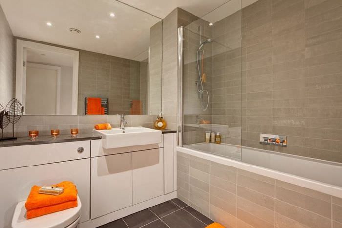 Оранжевое полотенце в ванной комнате с большим зеркалом