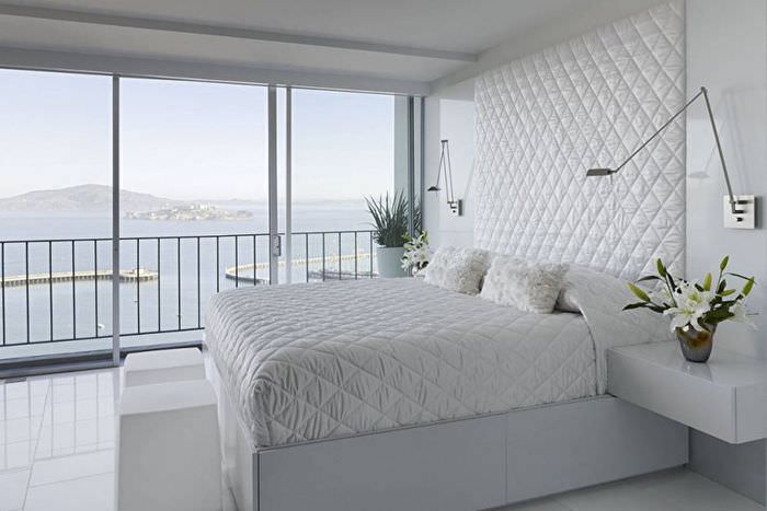 Белая кровать в спальне с панорамным окном