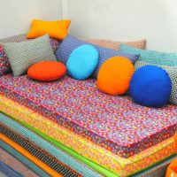 Яркие подушки из разноцветного материала для декора дивана