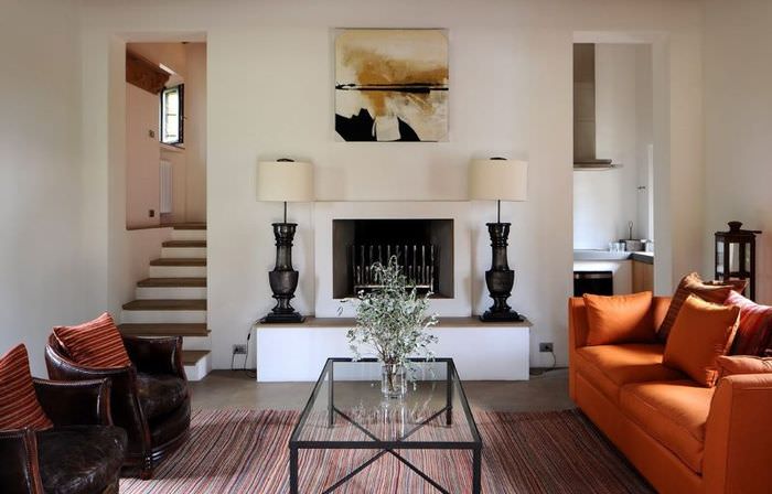 Оранжевый диван в интерьере гостиной с камином