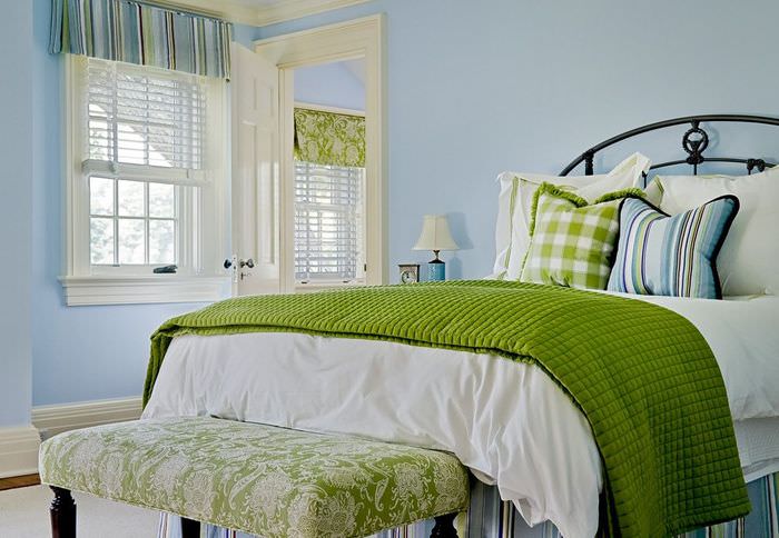Зеленое покрывало на кровати в спальне с голубыми стенами