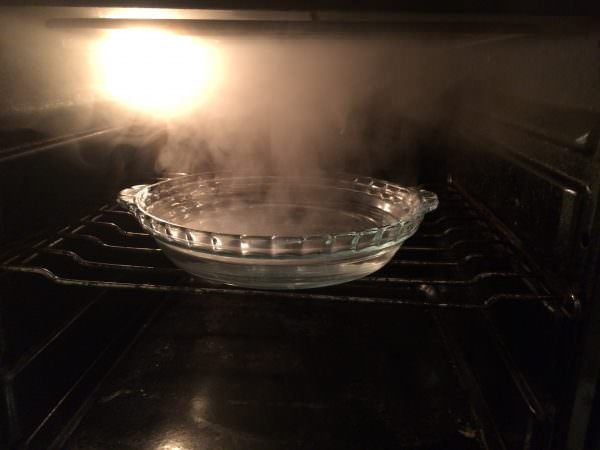 Прежде, чем приступить к очистке духовки, ее необходимо разогреть и поставить в нее кастрюлю с горячей водой, добавив немного уксуса. 