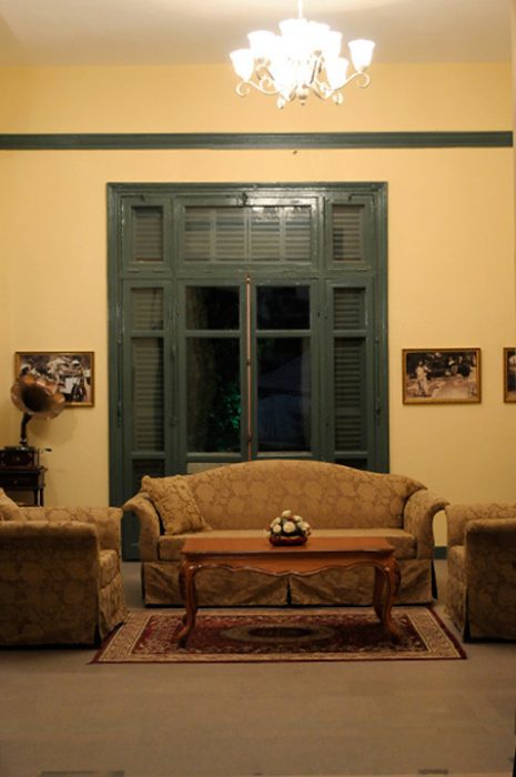 Бежевый диван на фоне окна с зелёными рамами